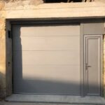 vue sur une porte de garage avec création d'une ossature acier pour installé une porte de service grise clair sur une façade pierre.Réalisation Rémy Ferere isère 38