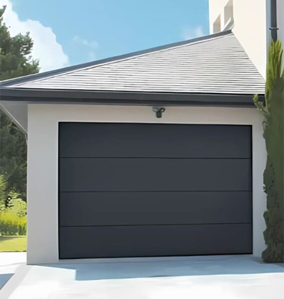 Une porte sectionnelle de garage noir au toit gris anthracite par Ferere Remy, pour cette construction neuve.